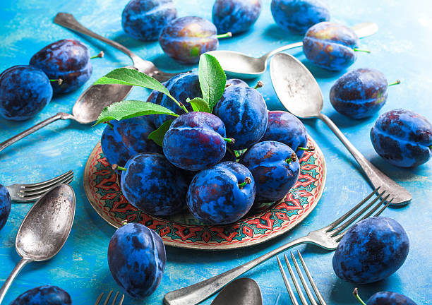 istock Plums group and leaves on plate with forks and spoons 625328928