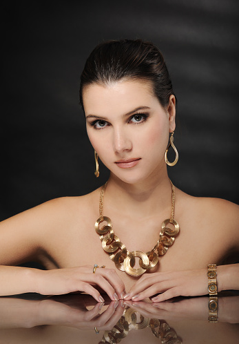 beautiful woman in golden jewelry on black background