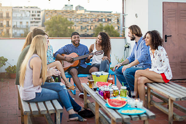 istock Happy man playing guitar for friends on terrace 625369924