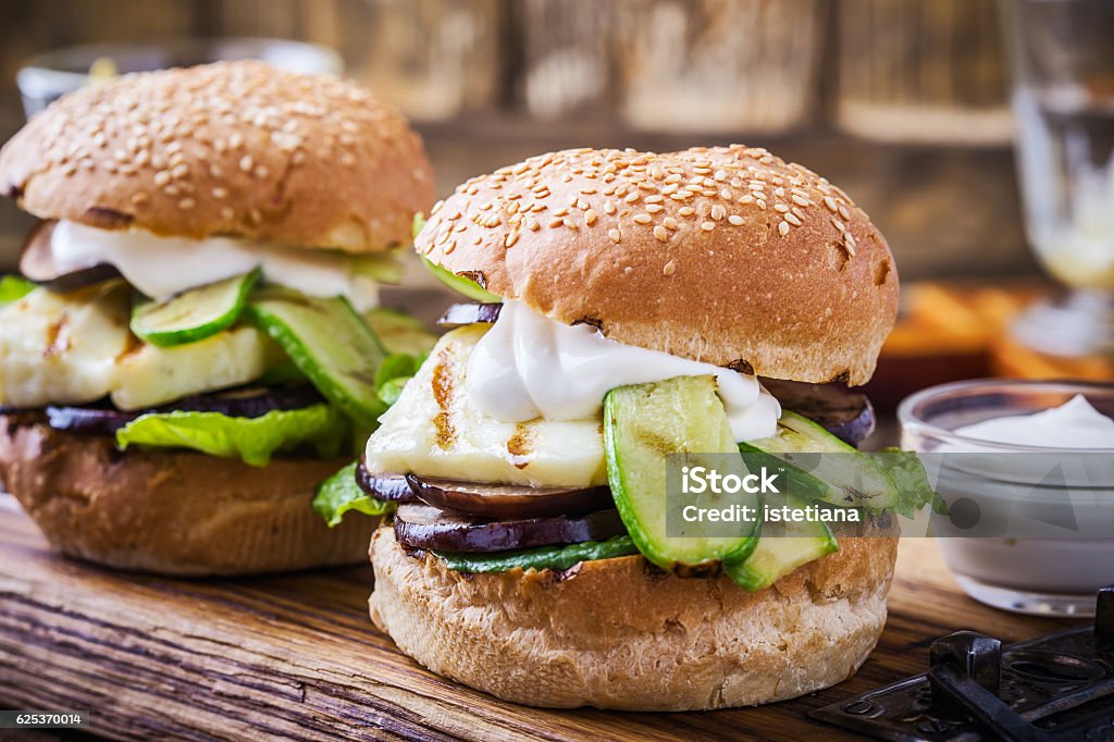 Grilled vegetable and haloumi burger with romaine lettuce Grilled vegetable and haloumi burger with romaine lettuce on wooden table Barbecue Grill Stock Photo