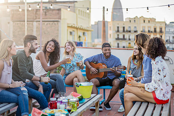 istock Cheerful man playing guitar for friends on terrace 625370112