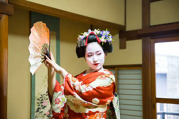 Maiko girl dancing with paper fan in Japanese tatami room