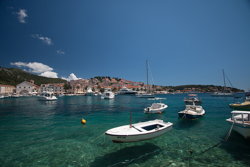 Small boats floating in a sunny Croatian harbour with crystal clear water.