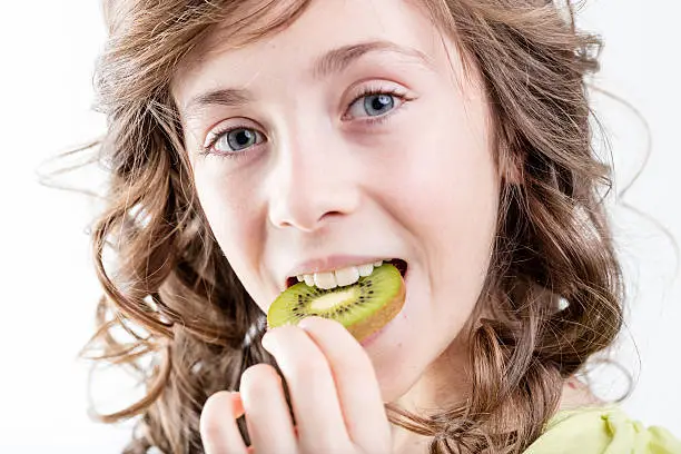 Photo of girl eating a kiwi slice