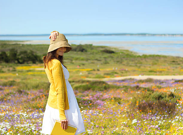 jovem no campo de flores segurando livro - west coast living - fotografias e filmes do acervo