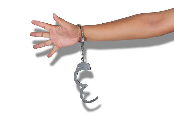 Photo of Handcuffs and hand on a white background