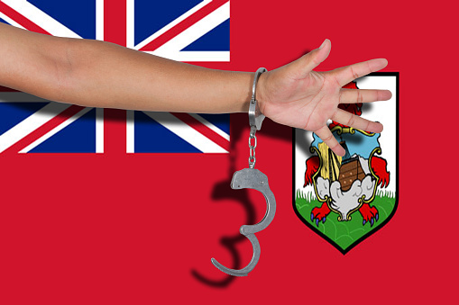 handcuffs with hand on Bermuda flag