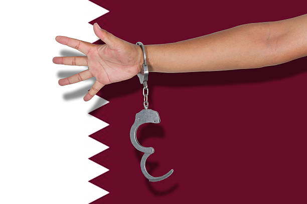 handcuffs with hand on Qatar flag stock photo