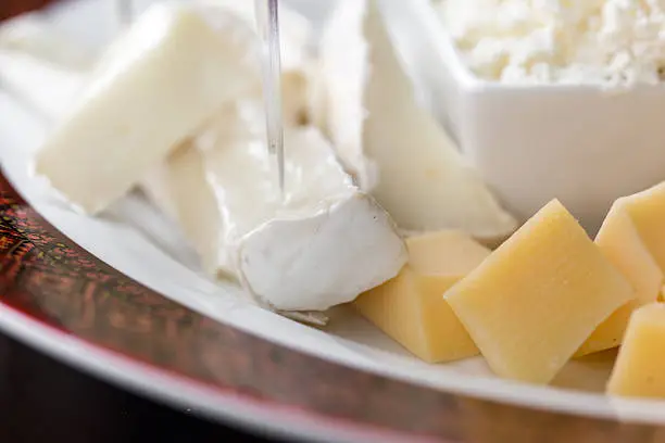 Set of different cheeses, brie cheese, mozzarella and feta cheese on plate close up