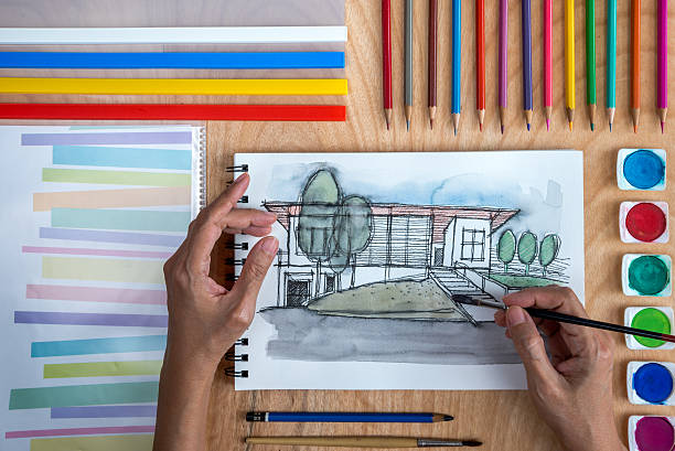 istock Designers hands drawing house illustration on notebook/ property business concept 625439342