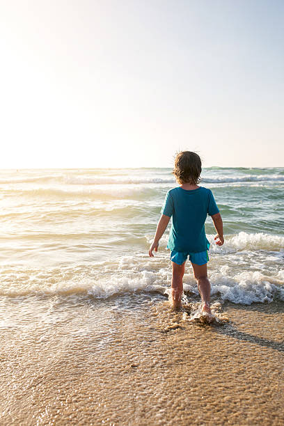 istock Rear view of small boy at the beach. 625443812