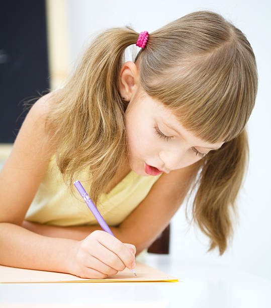 istock Little girl is writing using a pen 625451040