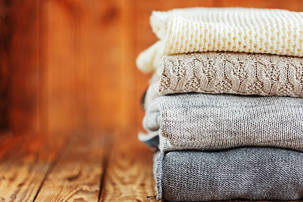 istock Stack of knitted winter clothes on wooden background, sweaters, space 625451950