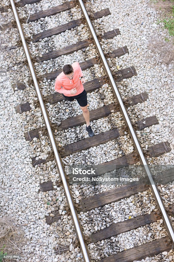 Jogging on railroad tracks Sporty young man running on railroad track. Aerial view. Health conscious concept. Jogging Stock Photo