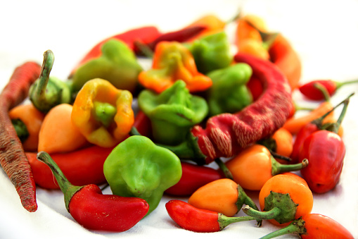 Mix of fresh colorful hot chili peppers on white background