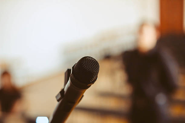 istock Microphone over the Abstract blurred photo of conference hall or 625457924