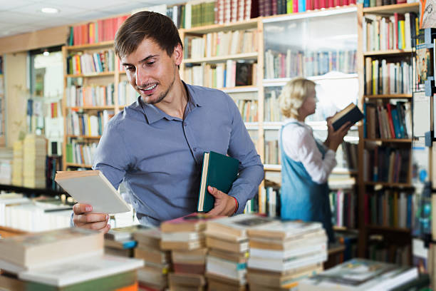 istock Young smiling man customer choosing new book 625467462
