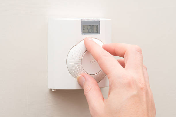 istock Hand Turning Dial on Wall Mounted Thermostat 625474618