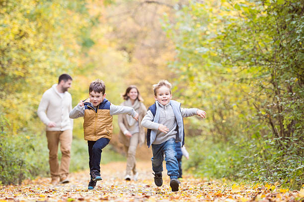 bella giovane famiglia in una passeggiata nella foresta autunnale. - autumn women leaf scarf foto e immagini stock