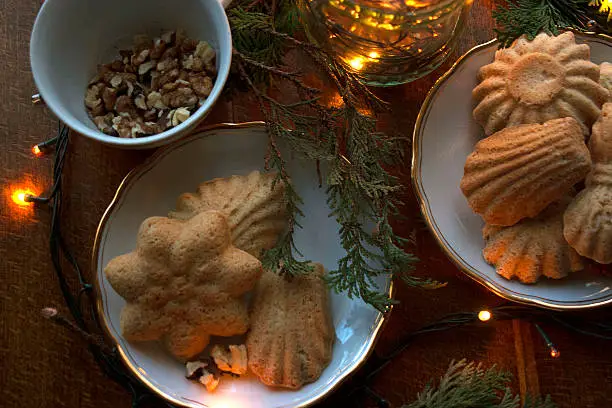 Gingerbread on a plate with walnuts in cup, fir-branches and Christmas bulbs.