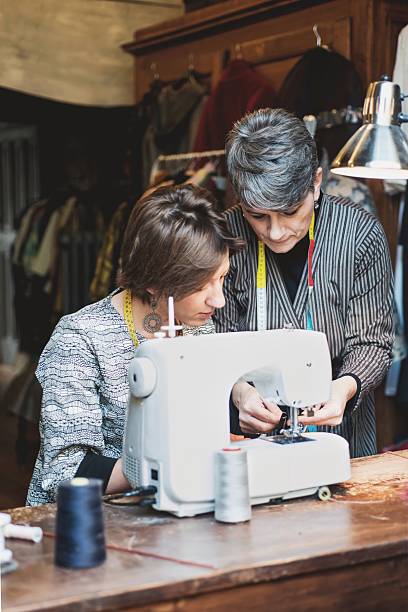 istock Seamstress Teaching her Assistant how to Use the Sewing Machine 625493992