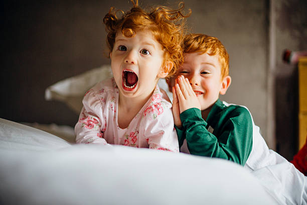 Morning Silliness Little girl and her older brother are being silly for the camera in the morning. They are in their pyjamas in their mother's bed. boy and girl looking at camera stock pictures, royalty-free photos & images