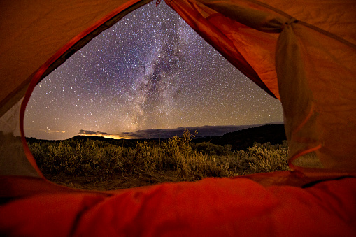 View of Milky Way Galaxy Looking Out Tent Camping - Landscape scenic at night astrophotography of sky full of stars with Milky Way band across sky.