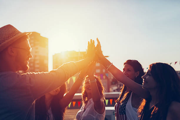 Group of friends at the rooftop doing high five Happy friends celebrating the success with high five teenage girls dusk city urban scene stock pictures, royalty-free photos & images