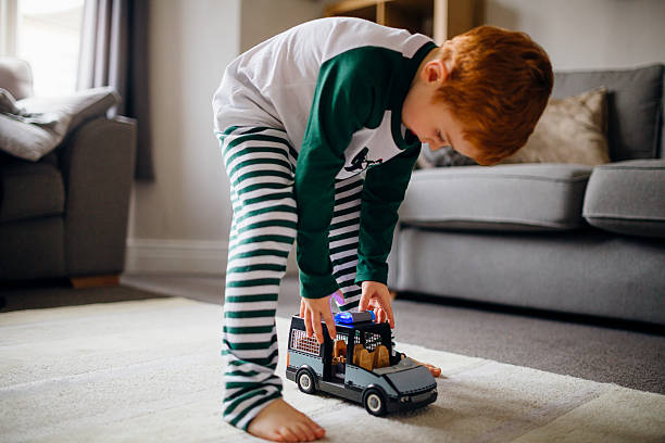 There's an Imaginary Emergency! Little boy pushing his toy police van along the rug in his home. kid toy car stock pictures, royalty-free photos & images