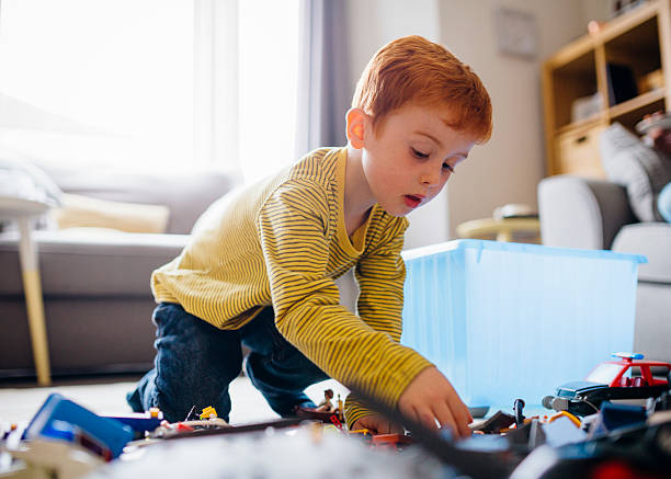 Playtime at Home Little boy at home playing with toys which he has tipped out from a box onto the floor. kid toy car stock pictures, royalty-free photos & images