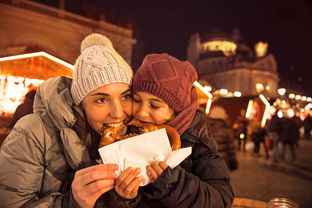 Family at the brezel market at christmas Mother and child christmas at christmas market in South Tyrol and Bite heartily into a brezel - vinatge look alto adige italy photos stock pictures, royalty-free photos & images