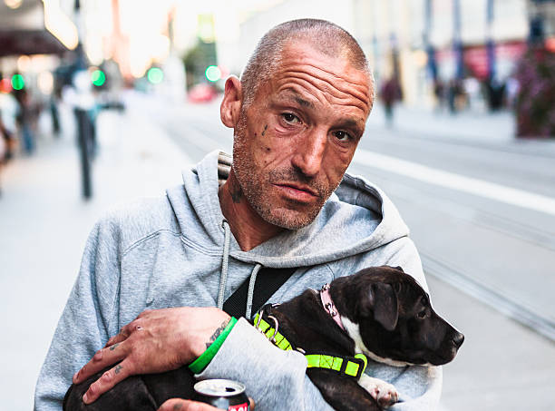Rough looking man holding a young dog stock photo