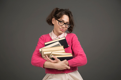 Cute, caucasian, nerd girl holding a stack of books
