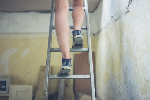 The legs of a young woman standing on a ladder to the loft