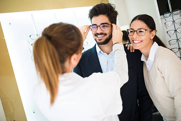 Smiling couple selecting eyeglasses in optical store