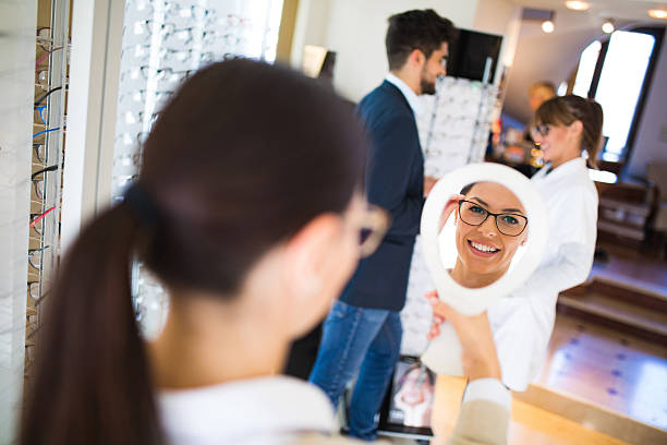 istock Woman choosing eyeglasses in optical store using mirror 625597434