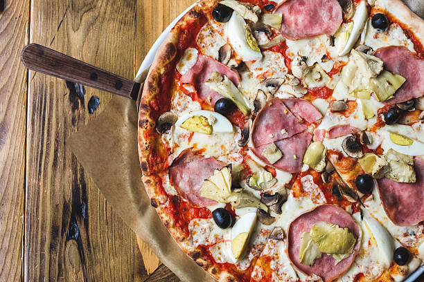 istock Fresh hot pizza with ham, artichokes, olives and tomatoes 625598464