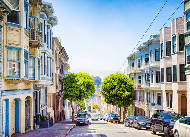 San Francisco hilly Pacific heights panoramic street view with parked cars and tramway wires.
