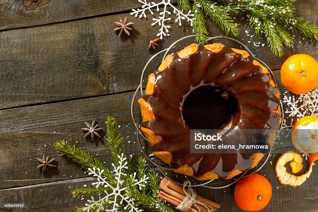 Christmas frame. Traditional homemade cupcake with chocolate ici Christmas frame. Traditional homemade cupcake with chocolate icing. Dessert new year decorations tangerines on vintage wooden background. Top view. Cake Stock Photo