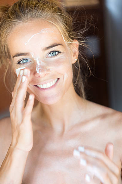 istock Woman putting moisturizer on her face, perfect candid smile 625650838