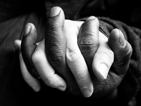 Interracial couple hold hands. Black and white photo.