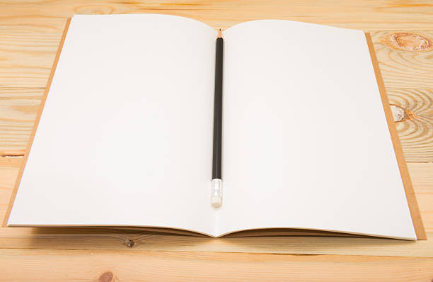 istock White open notebook and pencil on wood background. 625669700