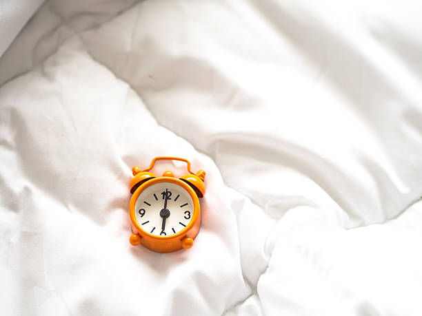 istock Alarm clock on bed in morning with sun light 625671440
