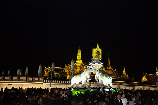 Bangkok, Thailand - October 23, 2016: Night condolence scene at Wat Phra Kaeo with elephant monument erected for King Bhumipol in 2011. Thai people are praying respect to Bhumipol.