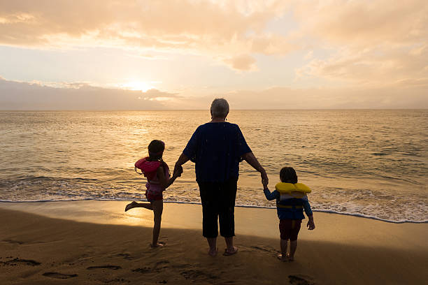 Grandma with grand daughters by the sea at sunset