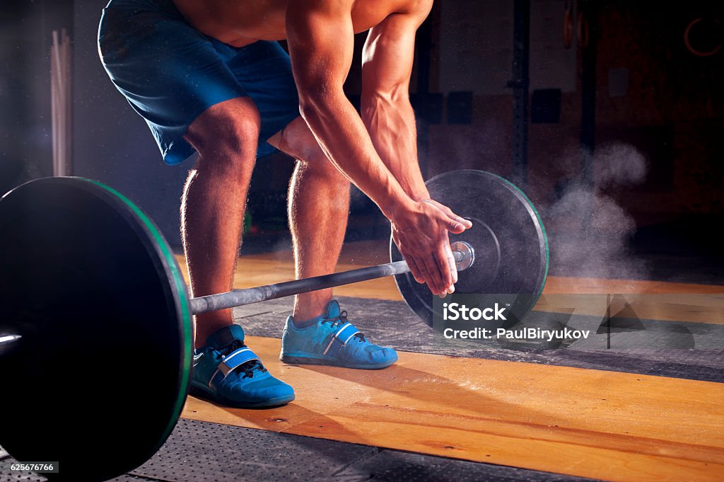 Young muscular man clapping hands with chalk Young sporty man with naked torso clapping hands with chalk powder, preparing for weightlifting training. gym, power lifting equipment. Sports, fitness - healthy lifestyle concept. Active Lifestyle Stock Photo