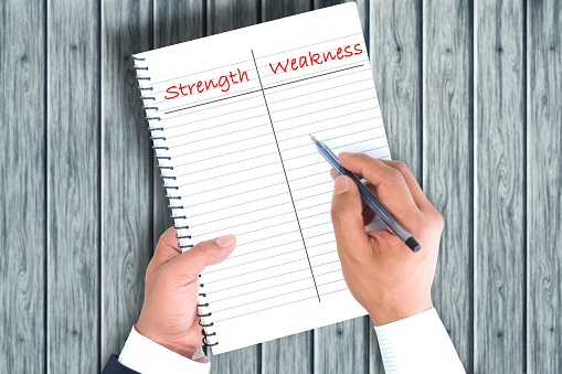 Businessman categorizing strengths and weaknesses into the paper