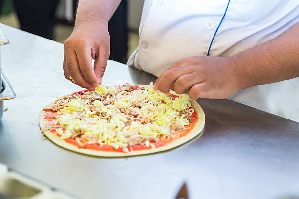 Male chef placing pizza toppings Male chef placing pizza toppings pizza topping stock pictures, royalty-free photos & images