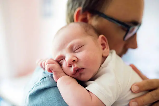 Photo of Close up of young father holding his newborn baby son