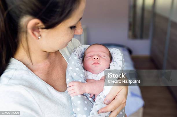 Beautiful Mother Holding Newborn Baby Son In Her Arms Stock Photo - Download Image Now